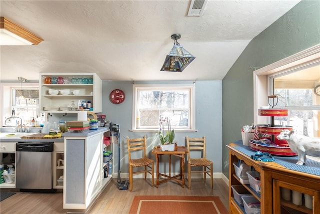 kitchen featuring visible vents, light wood-style floors, hanging light fixtures, dishwasher, and open shelves