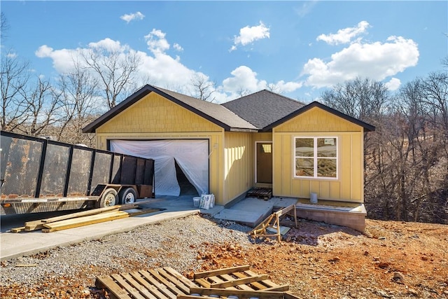 view of front of house with a garage, concrete driveway, and a shingled roof