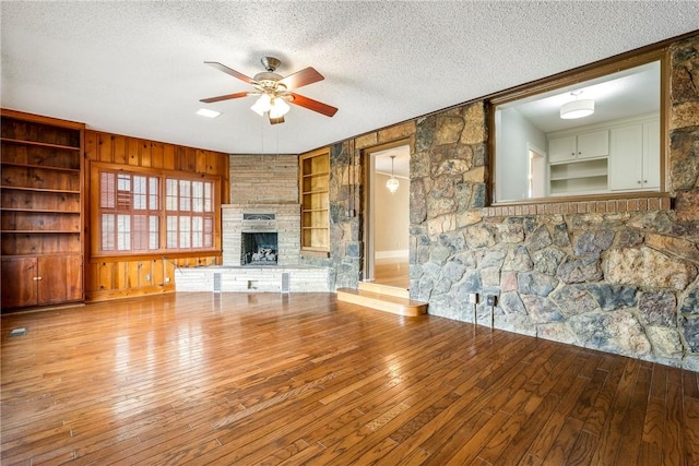 510 W Central Ave, Bentonville, AR 72712 - unfurnished living room with light wood finished floors, ceiling fan, a textured ceiling, a brick fireplace, and built in shelves