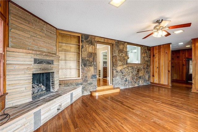 510 W Central Ave, Bentonville, AR 72712 - unfurnished living room featuring a textured ceiling, a large fireplace, wood finished floors, a ceiling fan, and built in features