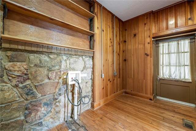 510 W Central Ave, Bentonville, AR 72712 - doorway featuring light wood finished floors, wooden walls, visible vents, and a textured ceiling