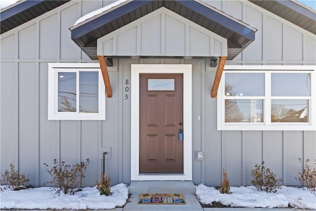 snow covered property entrance with board and batten siding