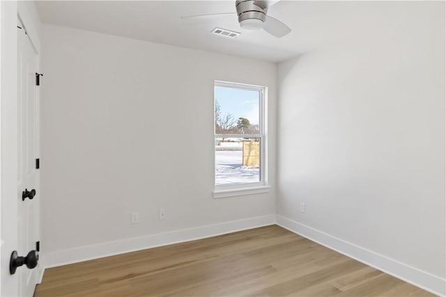 spare room with baseboards, a ceiling fan, visible vents, and light wood-style floors