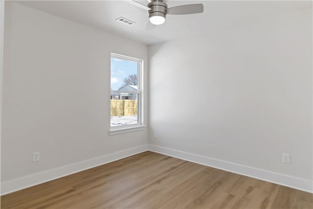 spare room with a ceiling fan, visible vents, baseboards, and wood finished floors