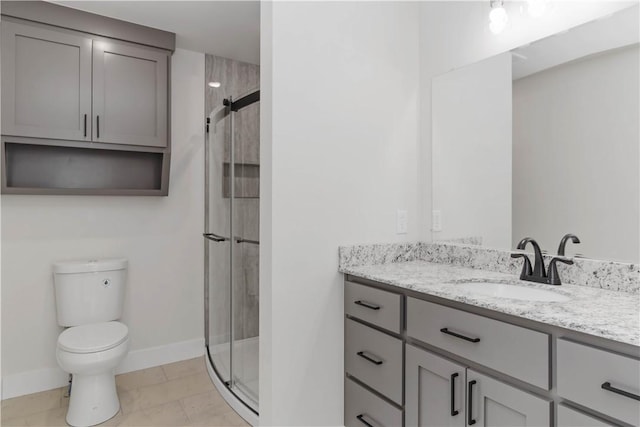 bathroom with toilet, a shower stall, baseboards, and vanity