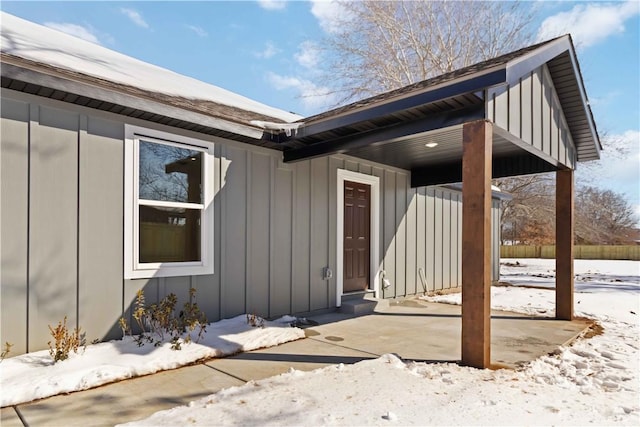 snow covered property entrance with board and batten siding