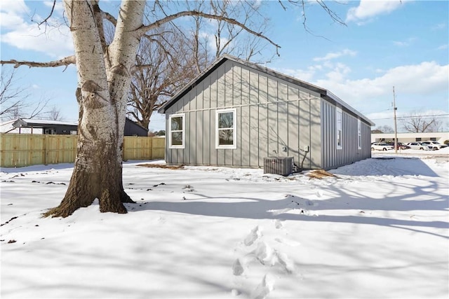 exterior space featuring board and batten siding, fence, and central air condition unit