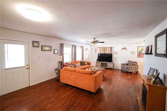 living area featuring dark wood-style floors, ceiling fan, and a textured ceiling