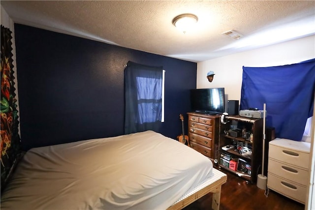 bedroom featuring dark wood-type flooring, visible vents, and a textured ceiling