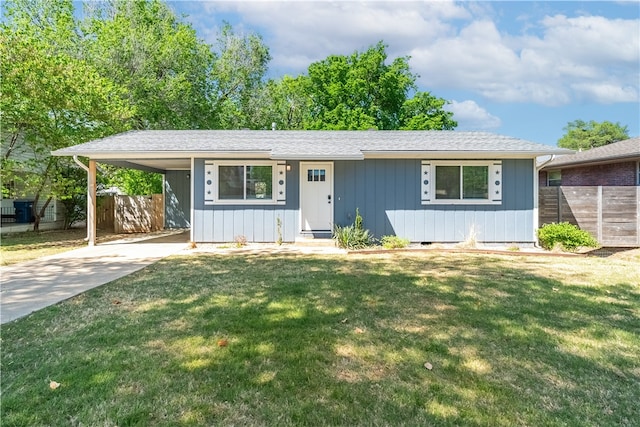 ranch-style house featuring an attached carport, concrete driveway, fence, and a front yard