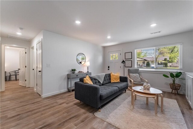 living area with recessed lighting, visible vents, baseboards, and wood finished floors