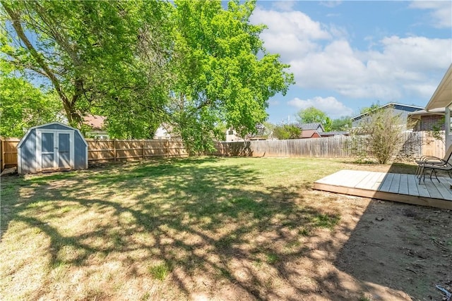 view of yard with an outbuilding, a fenced backyard, a wooden deck, and a shed