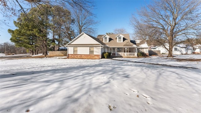 cape cod-style house with a porch, brick siding, and fence