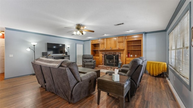 living area featuring dark wood finished floors, visible vents, ornamental molding, a brick fireplace, and ceiling fan