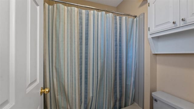 bathroom featuring a shower with shower curtain and toilet