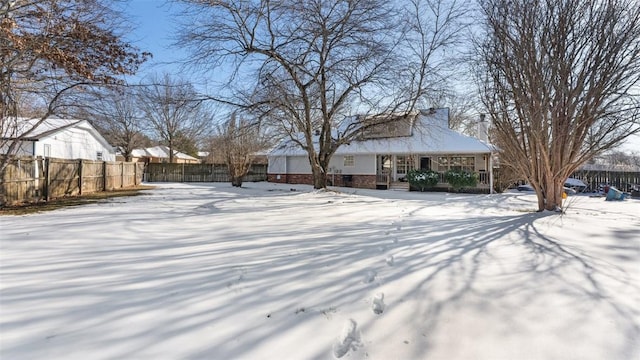 snowy yard featuring a porch and fence