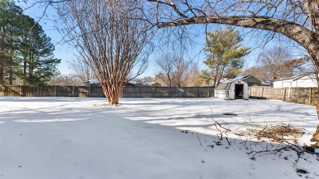 yard covered in snow featuring a storage shed, an outdoor structure, and a fenced backyard