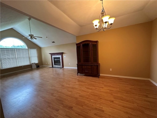 unfurnished living room with ceiling fan with notable chandelier, a tile fireplace, wood finished floors, and baseboards