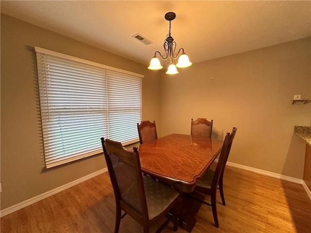 dining area with a chandelier, visible vents, light wood finished floors, and baseboards