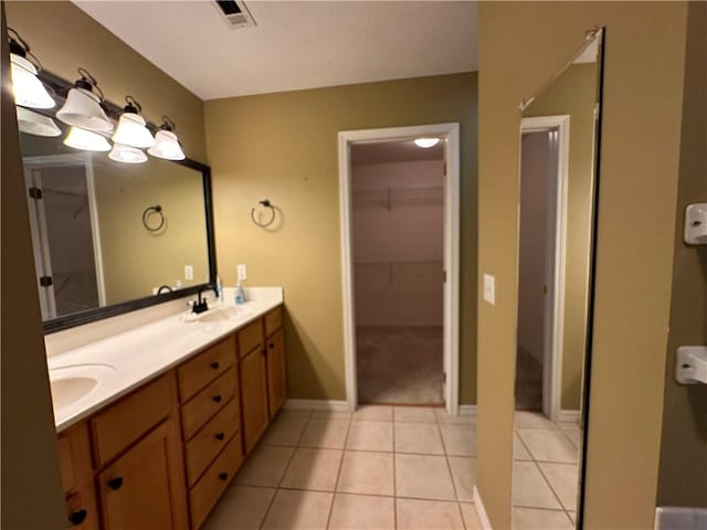 full bath featuring double vanity, visible vents, tile patterned flooring, a spacious closet, and a sink