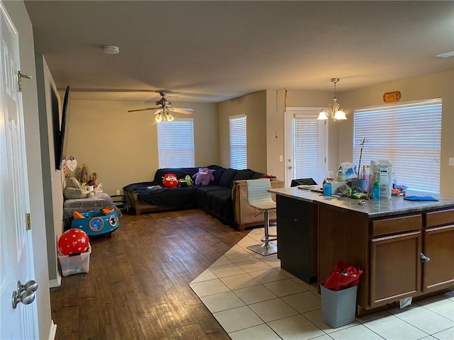 kitchen with hanging light fixtures, open floor plan, light wood-style flooring, and ceiling fan with notable chandelier