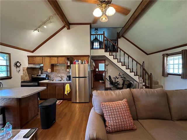 kitchen with dark wood finished floors, vaulted ceiling with beams, a sink, stainless steel appliances, and backsplash