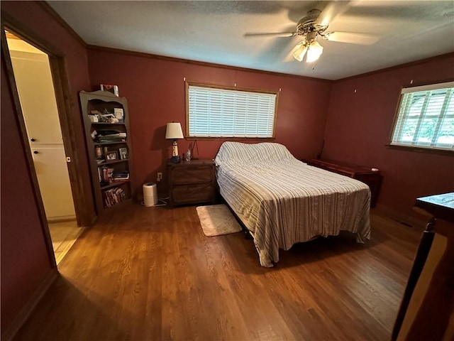 bedroom featuring dark wood-type flooring, crown molding, and ceiling fan