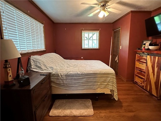 bedroom featuring ornamental molding, a ceiling fan, a closet, and wood finished floors