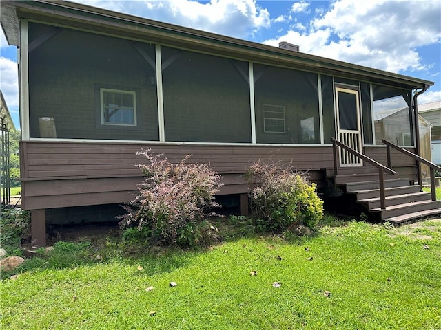 exterior space featuring entry steps, a front lawn, and a sunroom