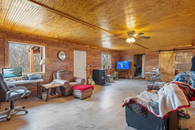 living room with a barn door, a ceiling fan, wooden ceiling, a wood stove, and wood walls