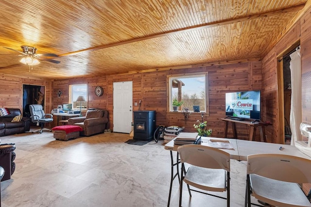 interior space featuring wood ceiling, a wood stove, plenty of natural light, and wooden walls