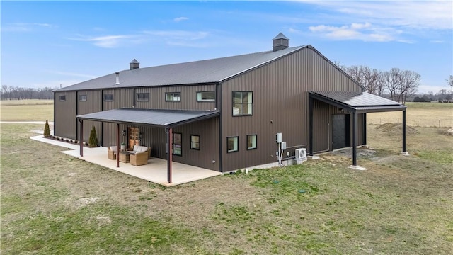 rear view of house featuring a patio area, metal roof, and a lawn