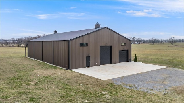 view of pole building with a rural view and a lawn