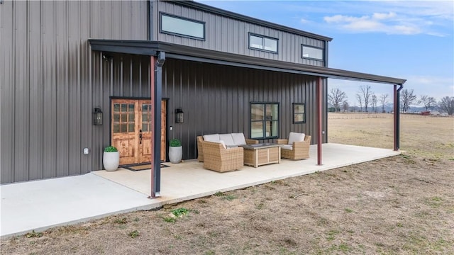 exterior space with board and batten siding, a patio, and an outdoor living space