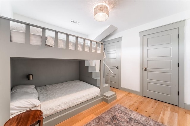 bedroom with light wood finished floors and visible vents