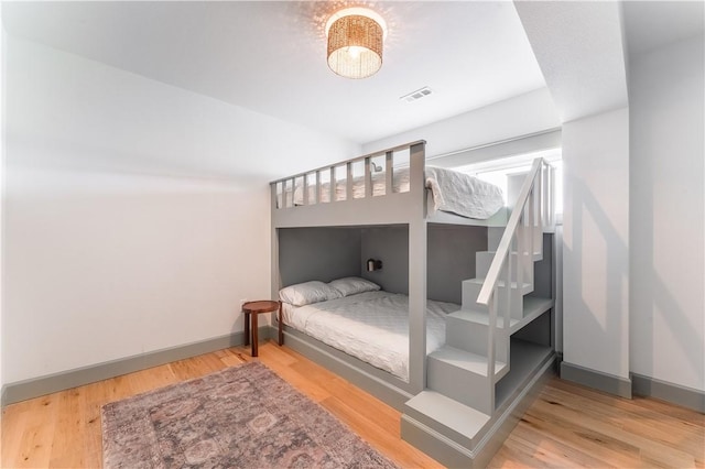 bedroom featuring baseboards, visible vents, and wood finished floors