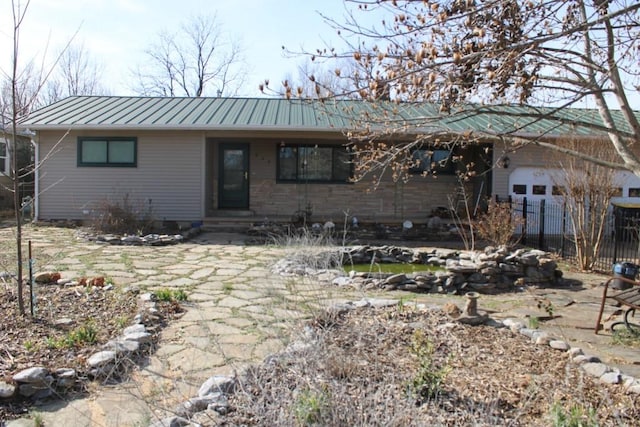 single story home featuring a garage, a standing seam roof, and metal roof