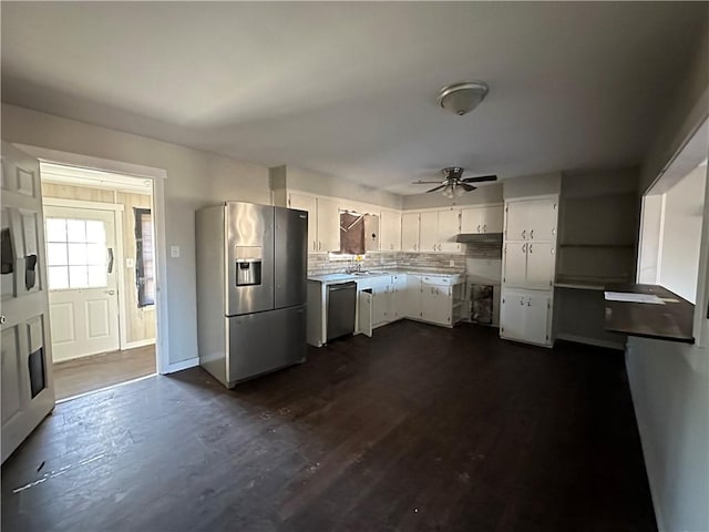 kitchen featuring dark wood-style flooring, light countertops, decorative backsplash, appliances with stainless steel finishes, and white cabinetry