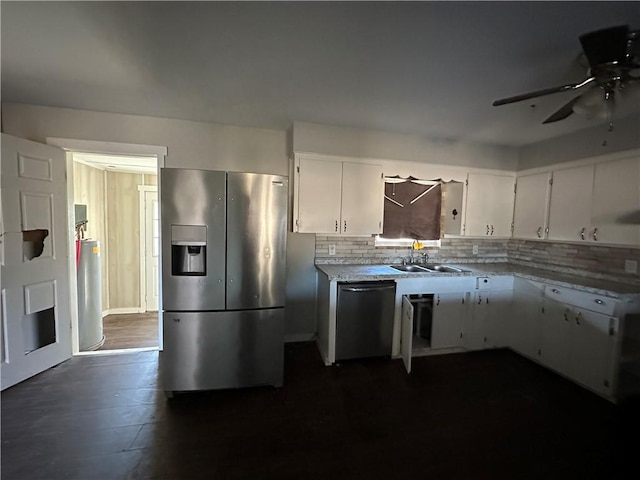 kitchen featuring tasteful backsplash, white cabinets, dark wood-type flooring, stainless steel appliances, and a sink