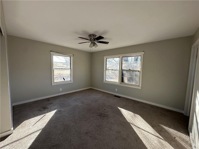 empty room with baseboards, visible vents, a ceiling fan, and carpet flooring