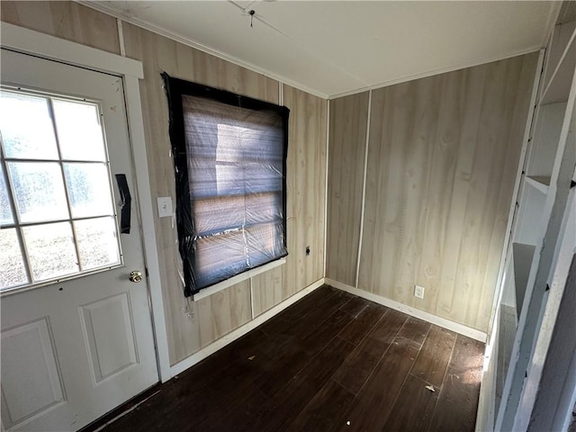 doorway to outside with crown molding, dark wood finished floors, and wooden walls