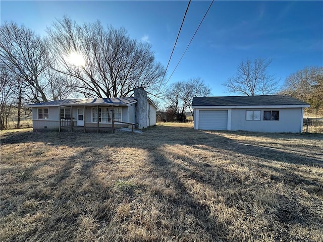 view of yard with an attached garage, dirt driveway, fence, and an outdoor structure