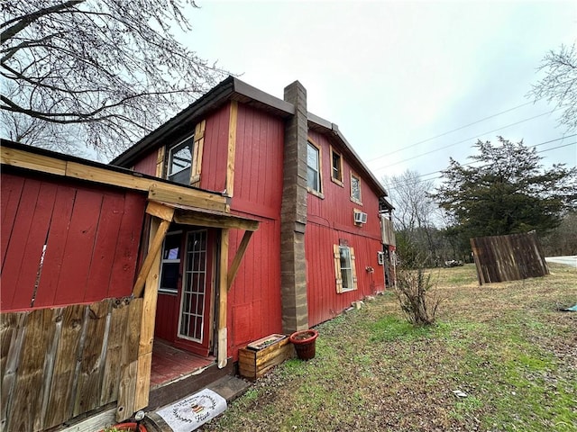 view of side of home with a chimney and a lawn