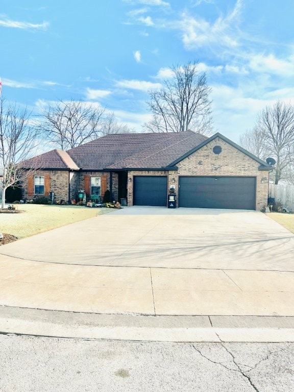 ranch-style house with a garage, concrete driveway, and brick siding