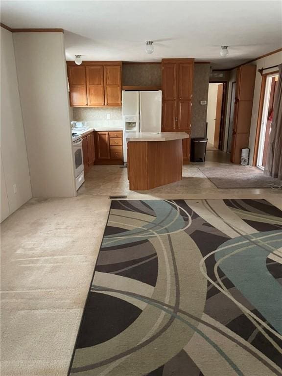 kitchen with white appliances, a kitchen island, brown cabinets, light countertops, and backsplash