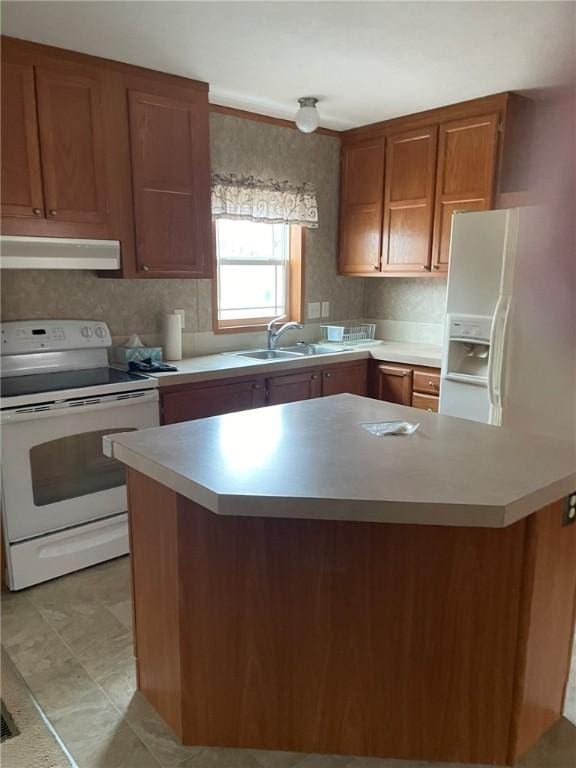 kitchen with white appliances, brown cabinetry, light countertops, under cabinet range hood, and a sink