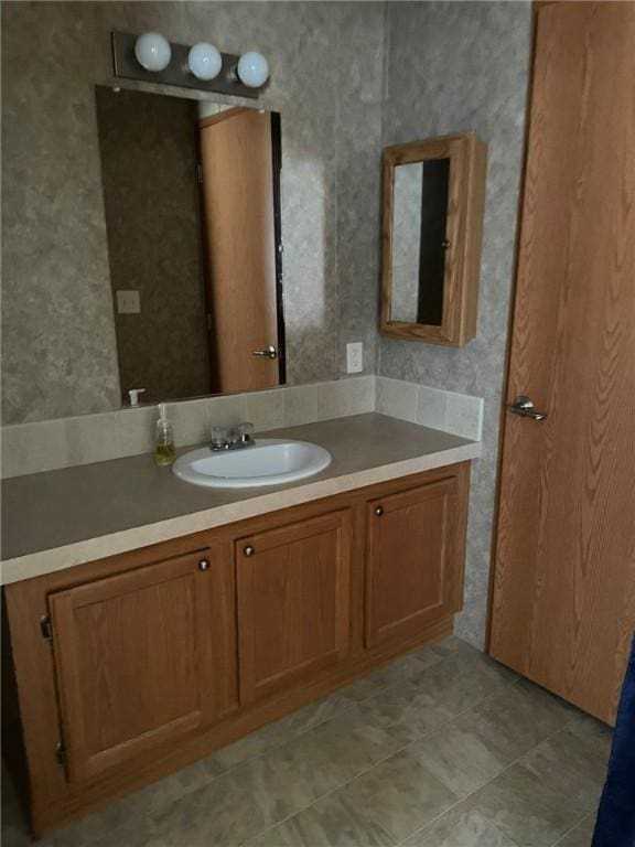 bathroom featuring tile patterned flooring, vanity, and wallpapered walls