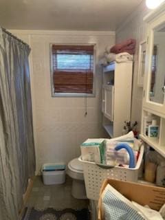 full bathroom with curtained shower, a decorative wall, toilet, and crown molding