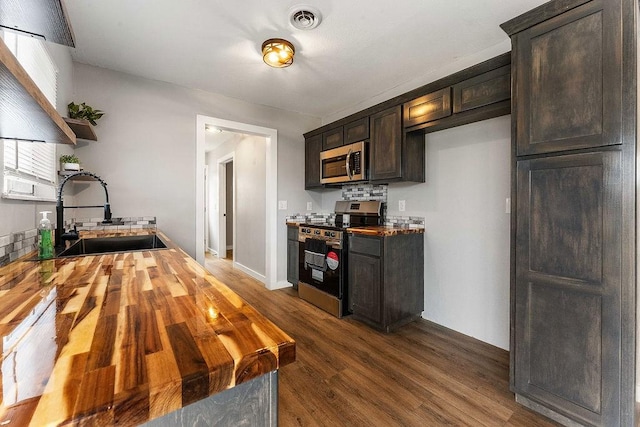 kitchen with visible vents, wooden counters, a sink, stainless steel appliances, and dark brown cabinetry