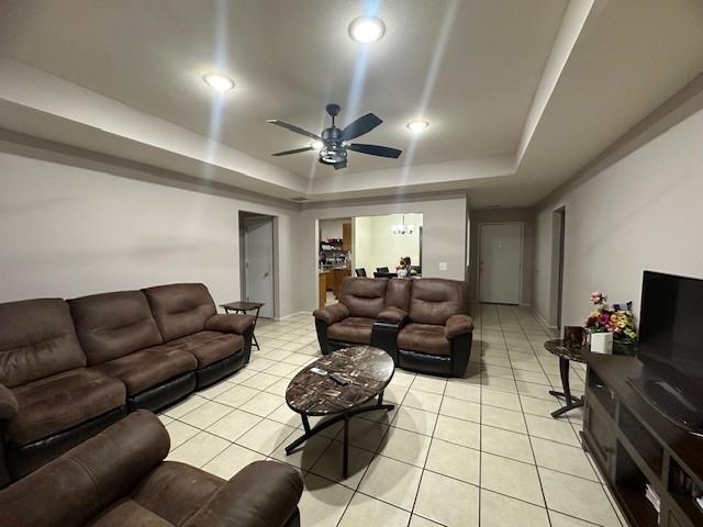 living area with light tile patterned floors, a raised ceiling, a ceiling fan, and recessed lighting